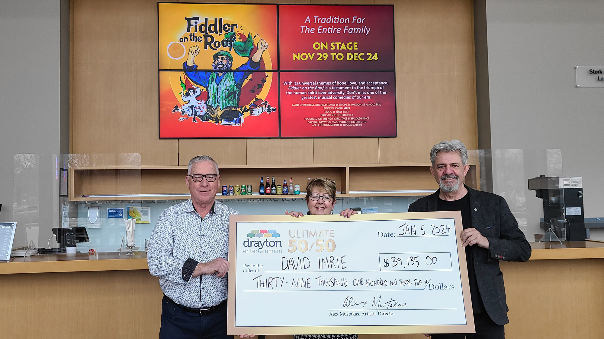 David and Wendy Imrie hold a big 50/50 cheque, alongside Alex Mustakas